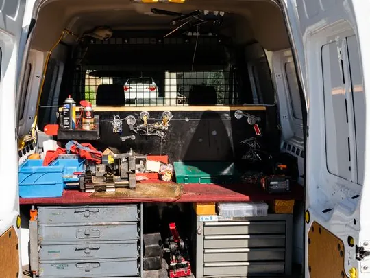 Inside the back of Jeff's van: a workbench with a key machine, parts drawers and tools.